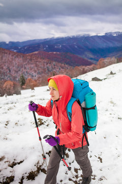 Girl with backpack walking on snow in the mountains.