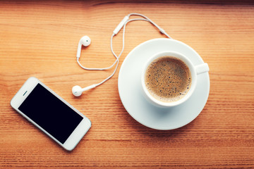 Fototapeta na wymiar Smartphone, headphones and coffee cup on wooden table
