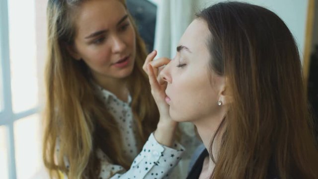 Young make-up artist makes a girl beautiful makeup for face closeup before an important event