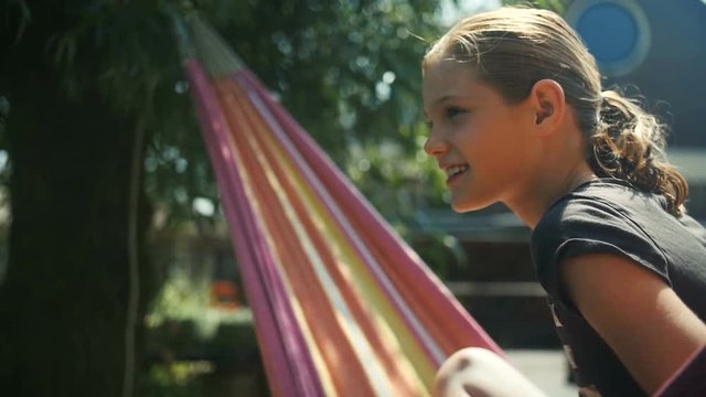 Slow motion shot of a girl relaxing in a hammock in the summer sun.
