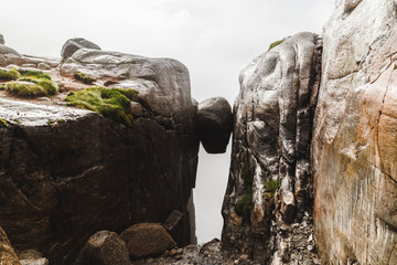 Kjeragbolten sight, famous norwegian nature landmark. Huge rock stone suspended between two neighbor mountains. Toning like instagram filter.