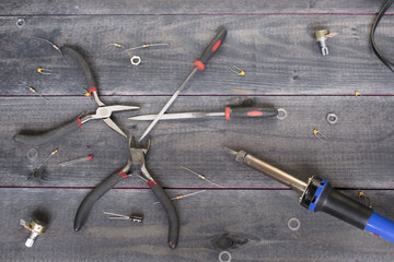 Different tools and a soldering iron on the wooden background.