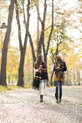 Young multiracial friends walking around autumn park