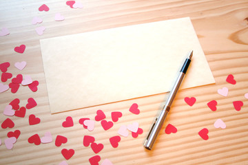 St Valentine's day: a love note for the loved one, with a fountain pen, pink and red hearts on a wooden table