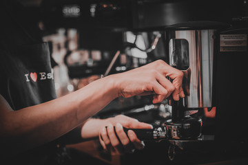 Barista making coffee with machine,stamp tool in cafe in vintage