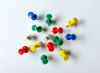 Many colored thumbtacks stuck into a white sheet of paper