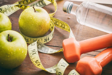 Green apples, dumbbells and measuring tape