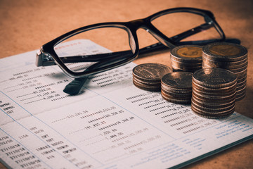 row of coins and eye glasses on account book in finance and bank