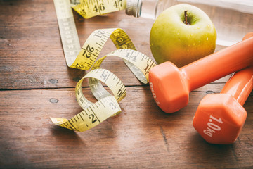 Green apple, dumbbells and measuring tape