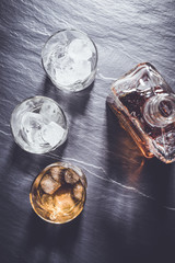 Glasses of whiskey with ice cubes on stone table. Top view