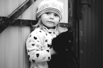 Little beautiful girl holding a cat in his hands