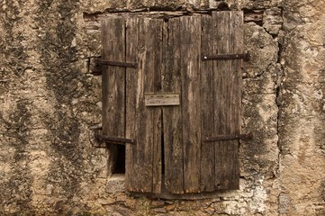 ancient wooden brown windows on decrepit grey plaster