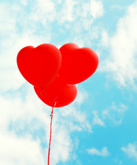 Fototapeta na wymiar Red air balloons heart shape flying over blue sky background