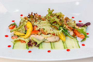 Salad with meat, vegetables and greens on a white plate