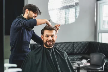 Cercles muraux Salon de coiffure Heureux mec se faire couper les cheveux par le coiffeur