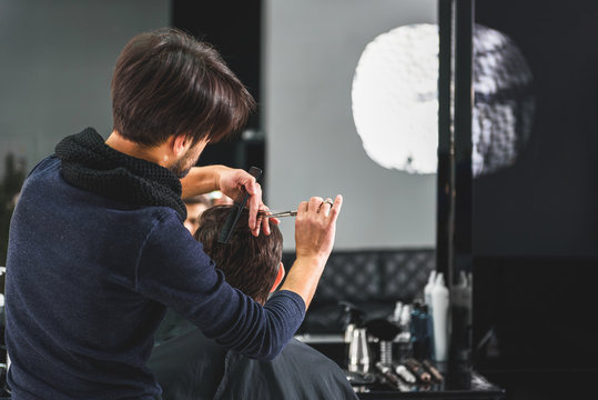 Professional stylist cutting male hair