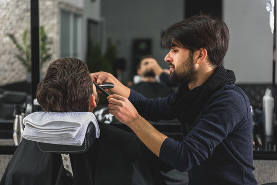 Confident barber serving customer at salon