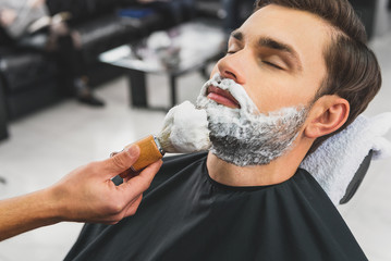 Skillful beautician preparing to shave stubble