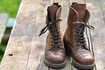 Коричневые кожаные ботинки со шнуровкой  на деревянной поверхности - obrazy, fototapety, plakaty