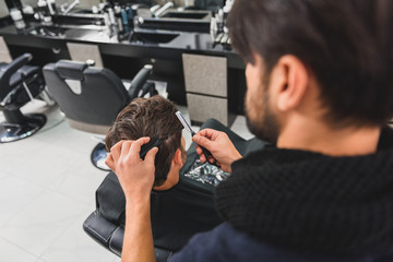 Skillful hairdresser cutting male hair