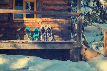 Snowshoes are on the porch of an old log cabin