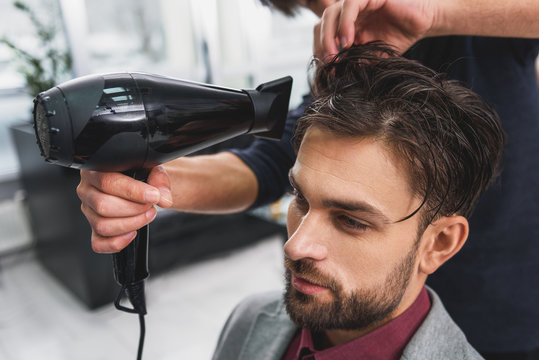 Skillful barber drying male hair at barbershop
