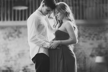 Portrait of happy couple awaiting the birth of the baby in loft interior.
