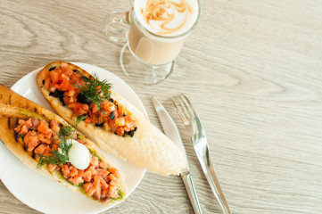Sandwich with salmon and tomatoes for breakfast. Coffee cappuccino. View from above