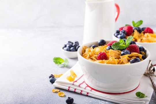 Healthy breakfast with corn flakes, berries and milk on light gray background. Copy space.