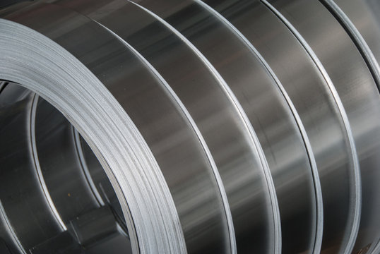 Aluminum sheet metal coils narrowed to size and stacked for packaging. Metal industry background