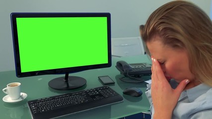 A young, attractive woman sits in front of a computer with a green screen in an office and shakes her head, frustrated - Powered by Adobe