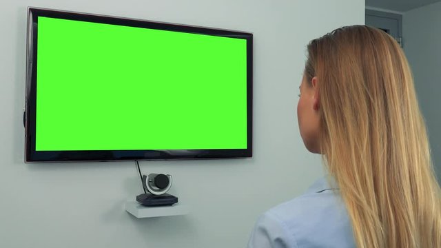 A Woman (the Back Of Her Head To The Camera) Looks At A Green Television Screen