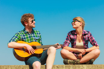 Fototapeta na wymiar Young man playing guitar to his girlfriend outdoor