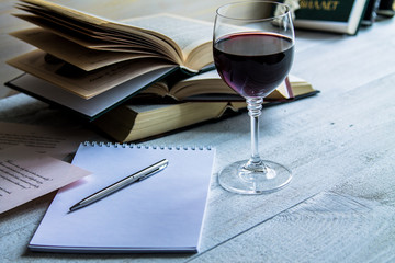 Glass of red wine and a book on a white wooden background