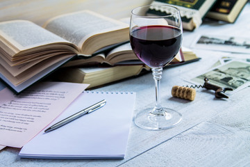Glass of red wine and a book on a white wooden background