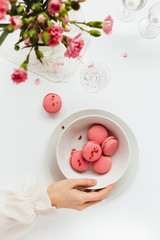 Overhead View of Woman Putting Bowl of Strawberry Macarons on White Table