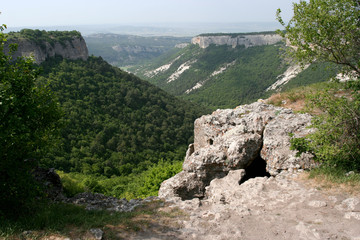 The summer mountain landscape with the artificial cave near the medieval fortress Mangup Kale in Crimea.