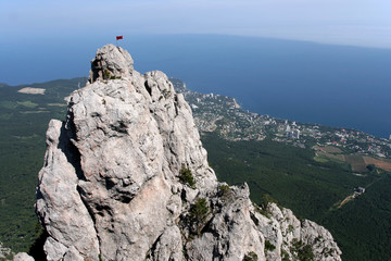 The red flag on the peak of Ai-Petri Mount and the landscape with Black Sea and Yalta in Crimea. 