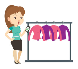 Woman shocked by price tag in clothing store.