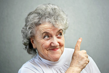 Thoughtful grandmother points a finger up - obrazy, fototapety, plakaty