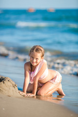 Fototapeta na wymiar Adorable happy little girl have fun at shallow water on beach vacation