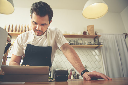 Worker noting acquire of visitor in cafe - Powered by Adobe