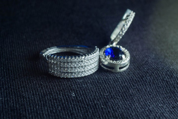 silver ring with a lot of white stones and silver earring with a blue stone
