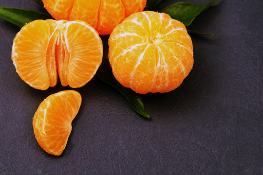 Fresh tangerines with leaves on dark background