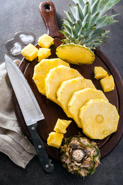 ripe sweet pineapple sliced on a cutting board and knife. stone