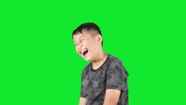 Funny little boy looks happy and laughing in the studio, shot with green background