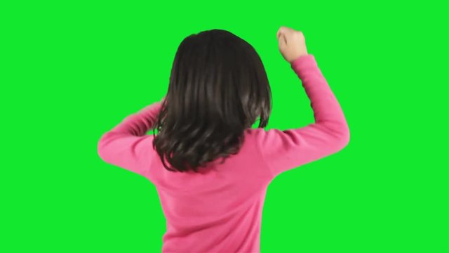 Cheerful little girl laughing in the studio while dancing with green background