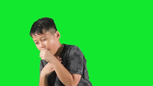 Cute little boy looks sick and coughing in the studio, shot with green background