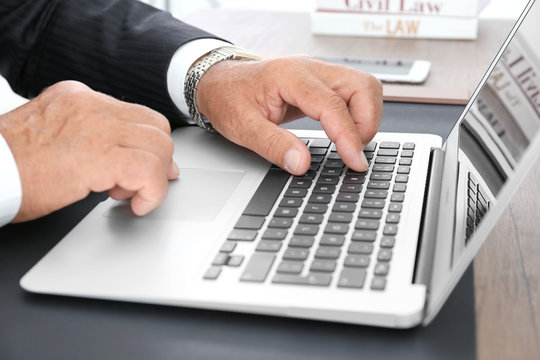 Male lawyer working with laptop in office, close up view