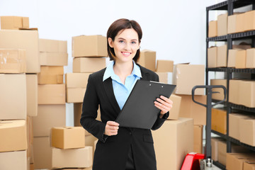 Young woman with clipboard in logistics company warehouse